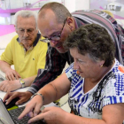 Laurentino López, en el centro, enseña a una mujer a manejar el ordenador en el centro CyL Digital de León. DL