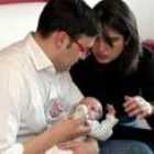 Un padre da el biberón a su hijo recién nacido en presencia de su madre