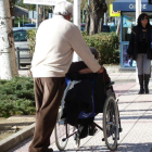 Un hombre empuja de una silla de ruedas por la calle. DL