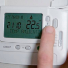 Una persona bajando la temperatura del termostato. DL