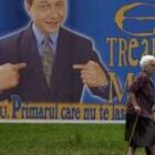 Una anciana camina por delante de uno de los carteles electorales de Basescu cuando se presentó
