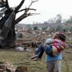 Una mujer lleva en brazos a una de las alumnas de la escuela devastada por el tornado, el lunes en Oklahoma.