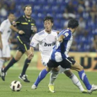 El debutante Mesut Özil (i), intenta marcharse del defensa del Hércules Francisco Peña (d).