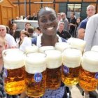 Una joven sostiene once jarras de cerveza para los alemanes congregados en Munich.