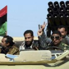 Rebeldes libios hacen el signo de la victoria a bordo de un vehículo dotado de lanzamisiles.