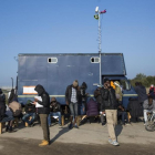 Inmigrantes del campamento francés de Calais usan teléfonos móviles junto a un camión que ofrece conectividad.