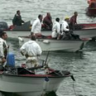 Los marineros utilizan palas y sus pequeños barcos para sacar el crudo de las rías