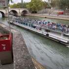 Un hombre utiliza un uritrottoir ante el paso de un bateau mouche en el Sena.