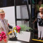 Un vecino de Puente Almuhey recibe el autobús de solteras con ramos de flores en la mano.