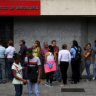 Ciudadanos venezolanos hacen cola en una cajero automático en una sucursal bancaria en Caracas, el viernes.