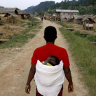Una mujer congoleña se dirige caminano con su hijo en la espalda hacia la aldea de Luvungi.