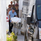 Un operario traslada al furgón fúnebre uno de los cadáveres hallados este miércoles en la localidad malagueña de Cortes de la Frontera.