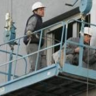 Dos trabajadores, ayer suspendidos sobre un andamio en la fachada de un edificio de La Rosaleda