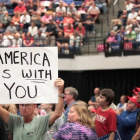 Un seguidor de Trump muestra un cartel con la frase "América te ama" en el mitin del presidente de Iowa.