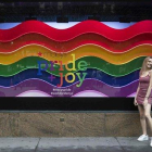 Una chica posa delante de un escaparate neoyorkino decorado con la bandera LGBTI en ocasión del día del Orgullo y el desfile del Pride.
