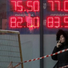 Una mujer, ante un panel que muestra el cambio del rublo ante el euro y el dólar, en Moscú.