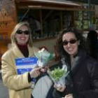 Dos mujeres muestran las plantas que recibieron a cambio del material para reciclar