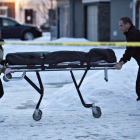 Dos agentes se llevan uno de los cadáveres encontrados en una casa de Edmonton, este martes.