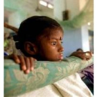 Una niña seropositiva permance en una cama de un hospital de la India