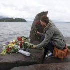 Una joven deja flores ante un monumento improvisado.