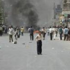 Una multitud de yemeníes junto a una barricada de neumáticos en llamas colocada por manifestantes