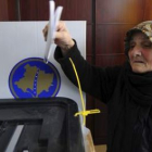 Una anciana deposita su voto en la urna.