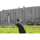 Un joven palestino lanza una piedra contra el muro que Israel ha levantado para aislar Palestina