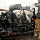 Un soldado americano se dispone a quitar los restos de uno de los coches bomba que explotaron ayer