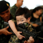 Un soldado tailandés muestra a un niño cómo funciona un arma en la celebración del Día del Niño.