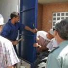 Operarios sellando la puerta ante la mirada del responsable de Unión Fenosa y un guardia civil