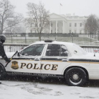 Un miembro del servicio secreto limpia la nieve de un vehículo en la Avenida Pennyslvania.