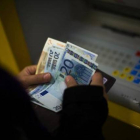 Una mujer saca dinero de un cajero automático.