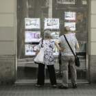 Una pareja consulta precios de pisos en una agencia inmobiliaria de Barcelona.