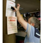 Un vecino pega un cartel en que se indica las restricciones de agua