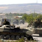 Un convoy ruso pasa junto a un tanque que bloquea una carretera