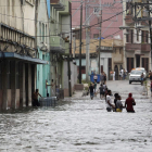 Varias personas caminan dentro del agua en una calle inundada de La Habana. ERNESTO MASTRASCUSA