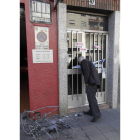 Un vecino mira por la puerta precintada por la Policía.