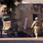 Soldados norteamericanos vigilan un blindado que acaba de sufrir un ataque en las calles de Bagdad