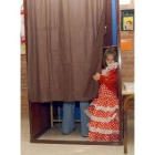 Una niña vestida de sevillana observa en un colegio electoral murciano