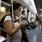 Una usuaria utiliza su móvil en el vagón de metro de la línea 3.