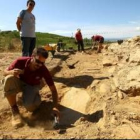 Uno de los excavadores limpia una laja de pizarra que marca una de las tumbas de la necrópolis