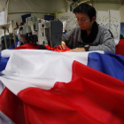 Una trabajadora de la empresa Doublet cose una bandera francesa, ayer en Lille.