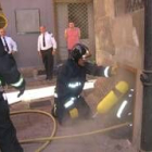 Uno de los bomberos se introduce por un hueco en el sótano