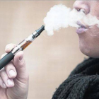 Una fumadora de cigarrillo electrónico exhala vapor tras una inhalación.
