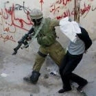 Un soldado conduce, esposado y encapuchado, a un palestino detenido