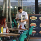 Un camarero sirve a unos clientes en una terraza.