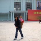 Una mujer pasea con una niña ante un retrato de Mao en una estación de tren de Shaoshan, en China.