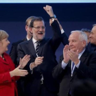 El presidente del Consejo Europeo, Donald Tusk, levanta el brazo de Rajoy en presencia de Angela Merkel y otros dirigentes populares europeos.