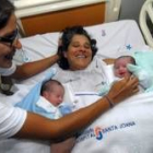 La brasileña Rozinete Cláudia Michelle mira a sus hijos y a su madre, en la cama tras dar a luz