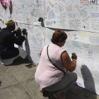 Varias personas escriben mensajes de condolencia junto a la Grenfell Tower. ANDY RAIN